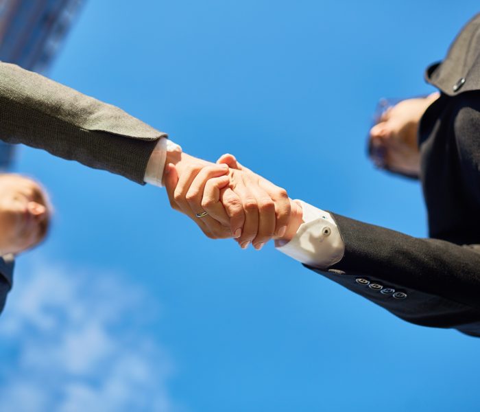 Handshake of partners and blue sky above